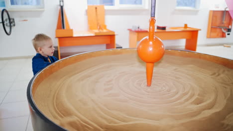science museum. kids playing with a sand pendulum at a science activity centre