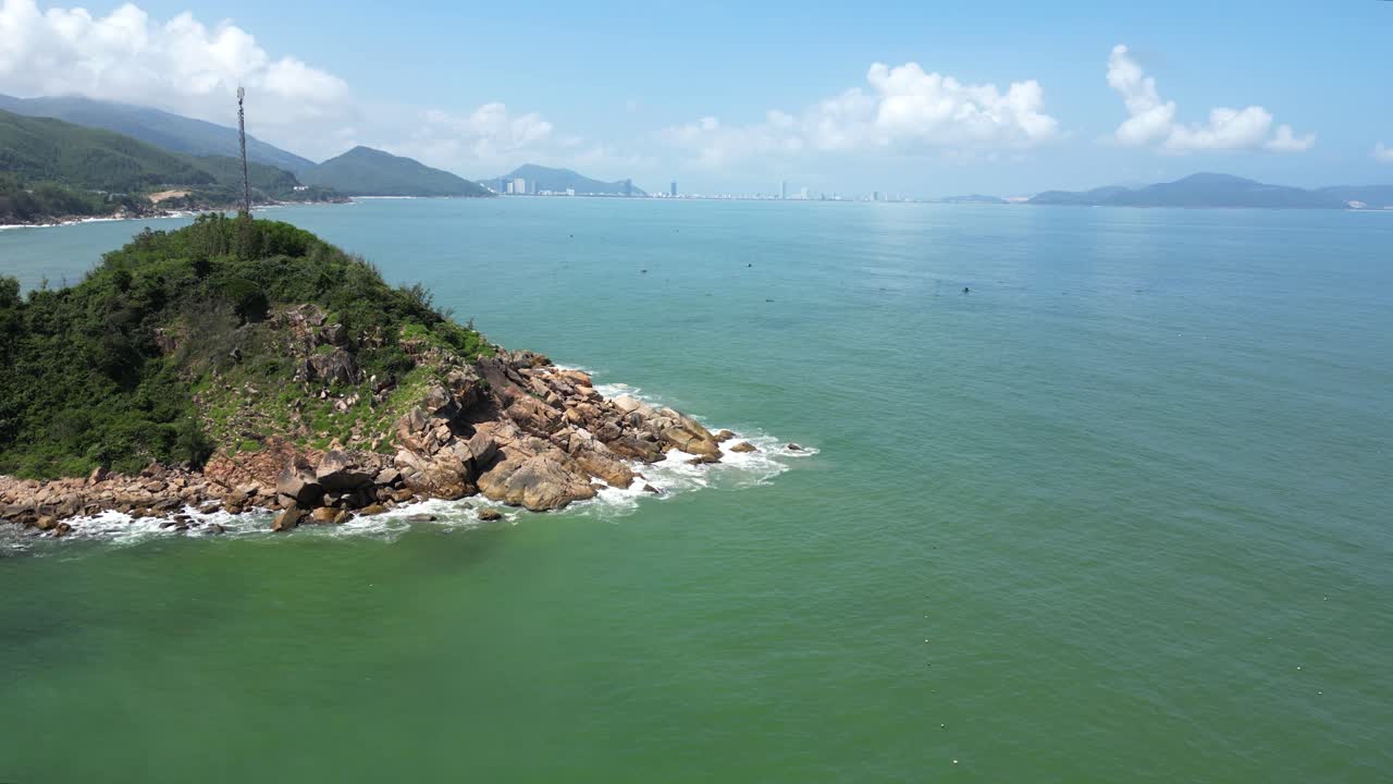 Forward drone flight over island with Quy Nhon city skyline in distance