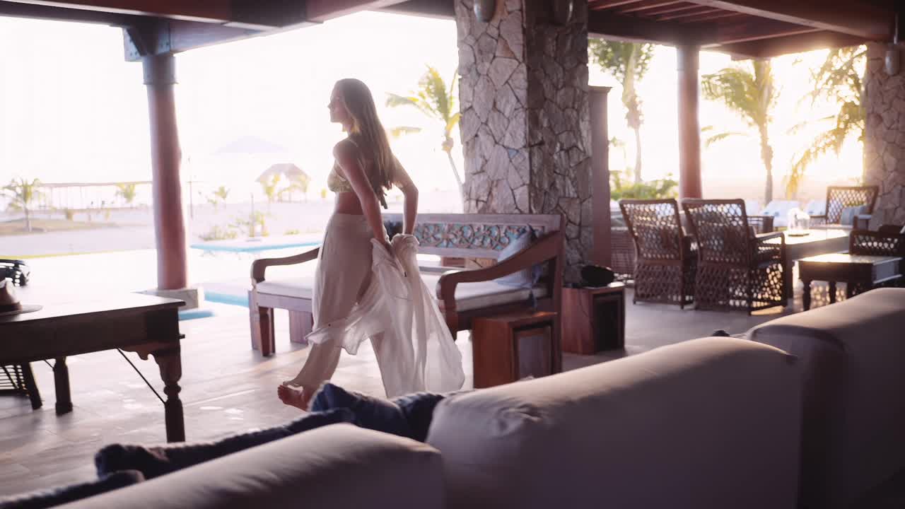 woman in a flowing white outfit walks through a private luxury beach hotel