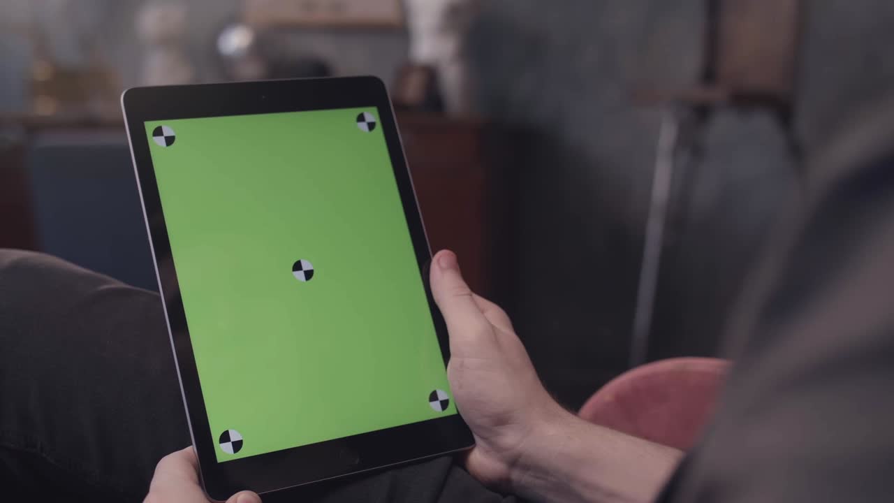 persona que sostiene una tableta con una pantalla verde