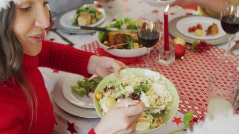 mujer caucásica feliz con sombrero de santa aplicando ensalada en el plato