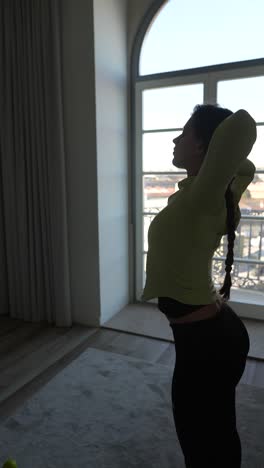 mujer estirándose por una gran ventana
