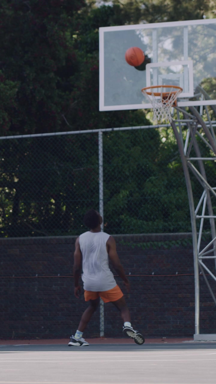 Giovani uomini che giocano a basket su un campo all'aperto.