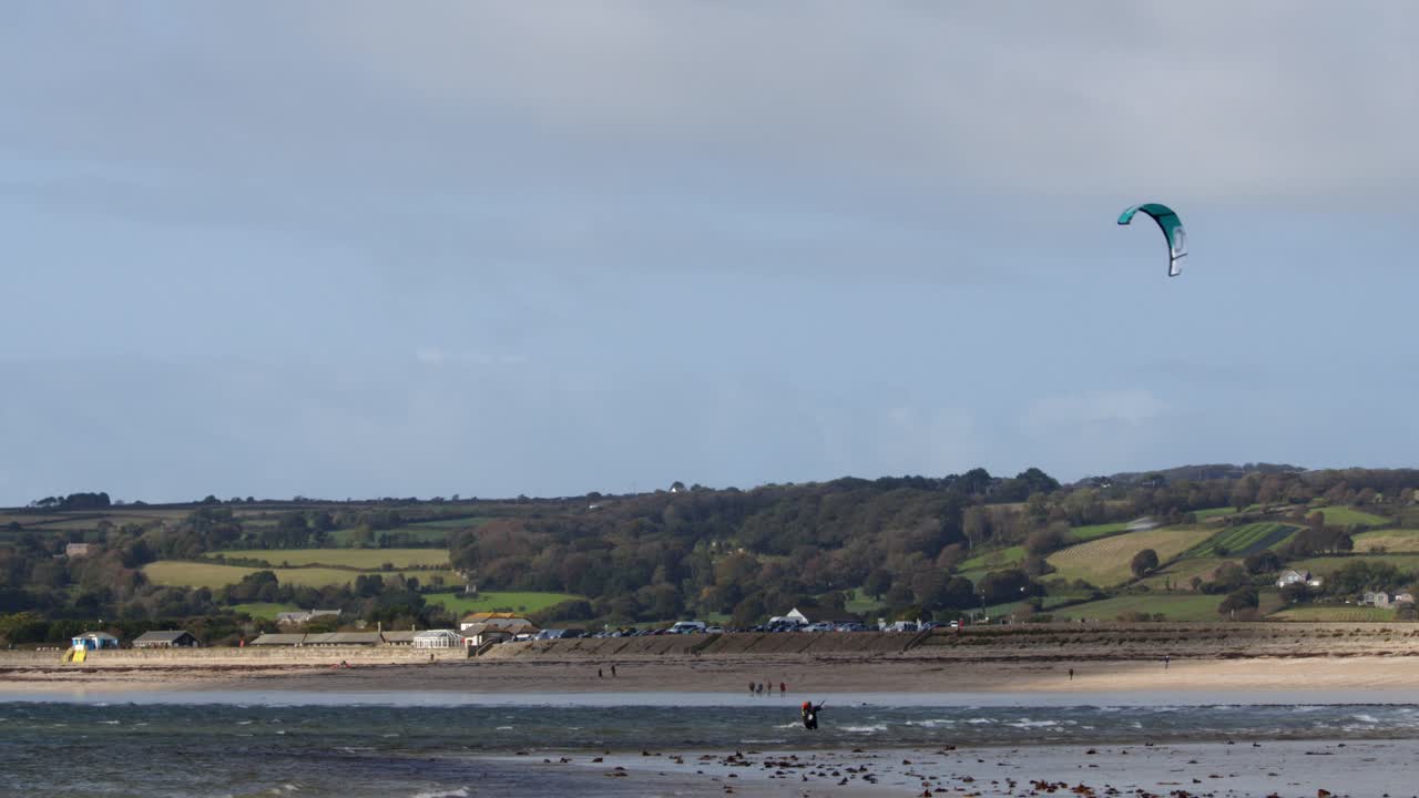 tiro largo de la playa de mount bay en marea baja con un surfista de cometas en el aire