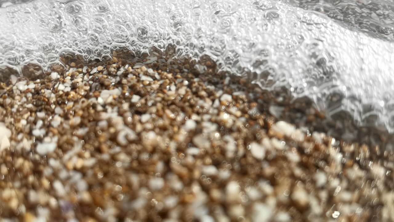 imágenes en cámara lenta del mar salpicando conchas y guijarros