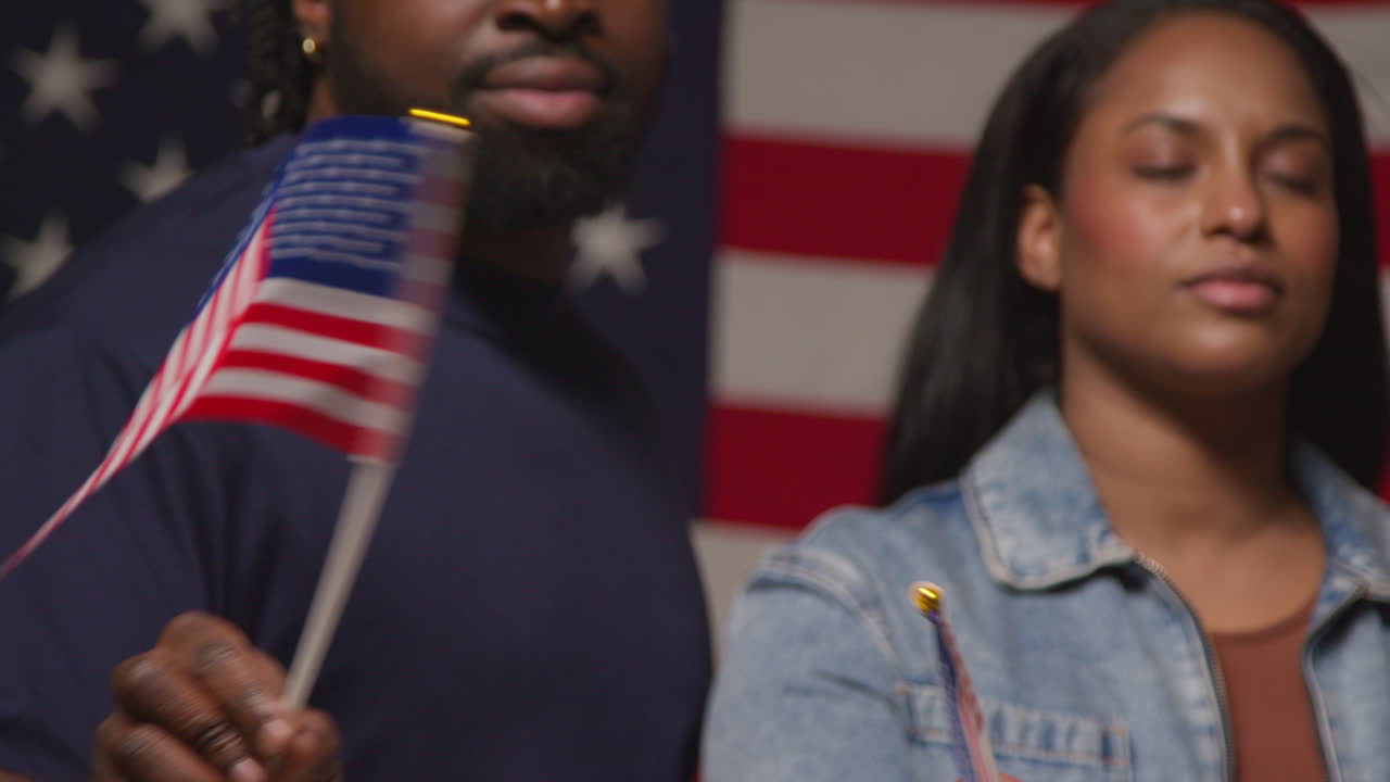 미국 국기 앞에 미니어처 별과 줄무 발을 흔들고 있는 커플의 스튜디오 초상화, 7월 4일 독립기념일을 축하하는 파티