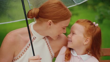 mother and daughter under umbrella in rain