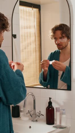 man applying facial masks in bathroom