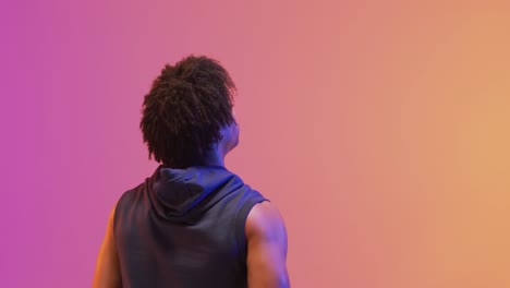 Video-of-rear-view-of-biracial-male-basketball-player-with-ball-on-orange-to-pink-background