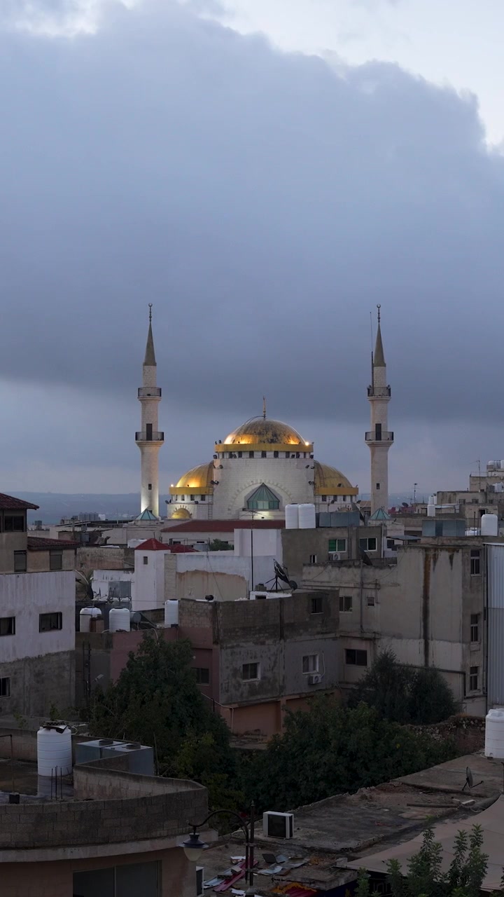 La Moschea Re Hussein si erge sopra Madaba, Giordania, sotto cieli nuvolosi drammatici che lentamente iniziano a dissiparsi e schiarirsi, time lapse verticale.