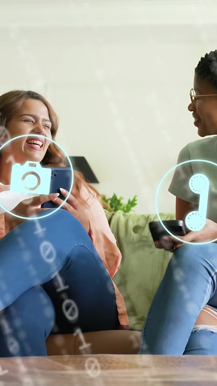 Vertical video: Two women on couch, animated tech overlay appearing, tilting phones and sharing