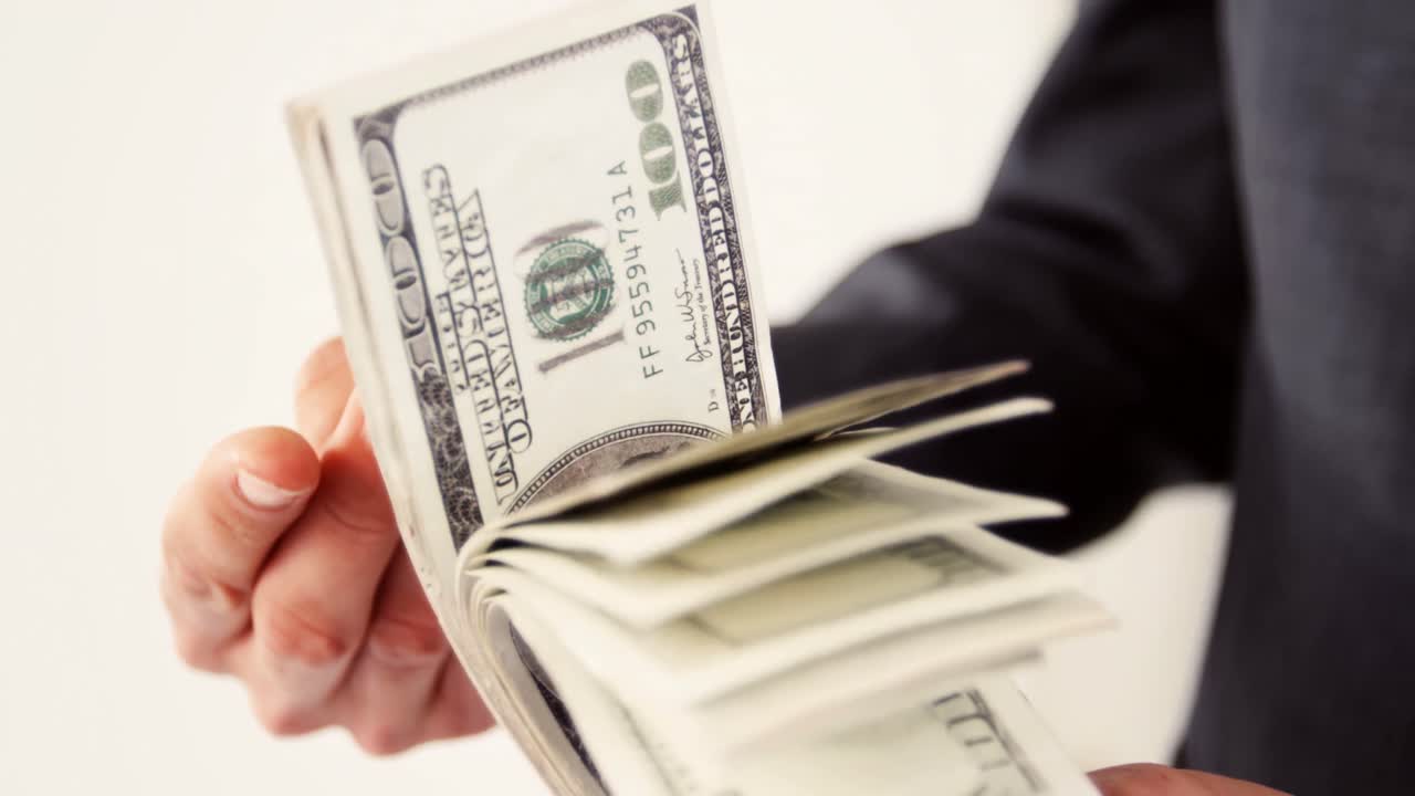 sección media de un hombre volviendo un billete de cien dólares