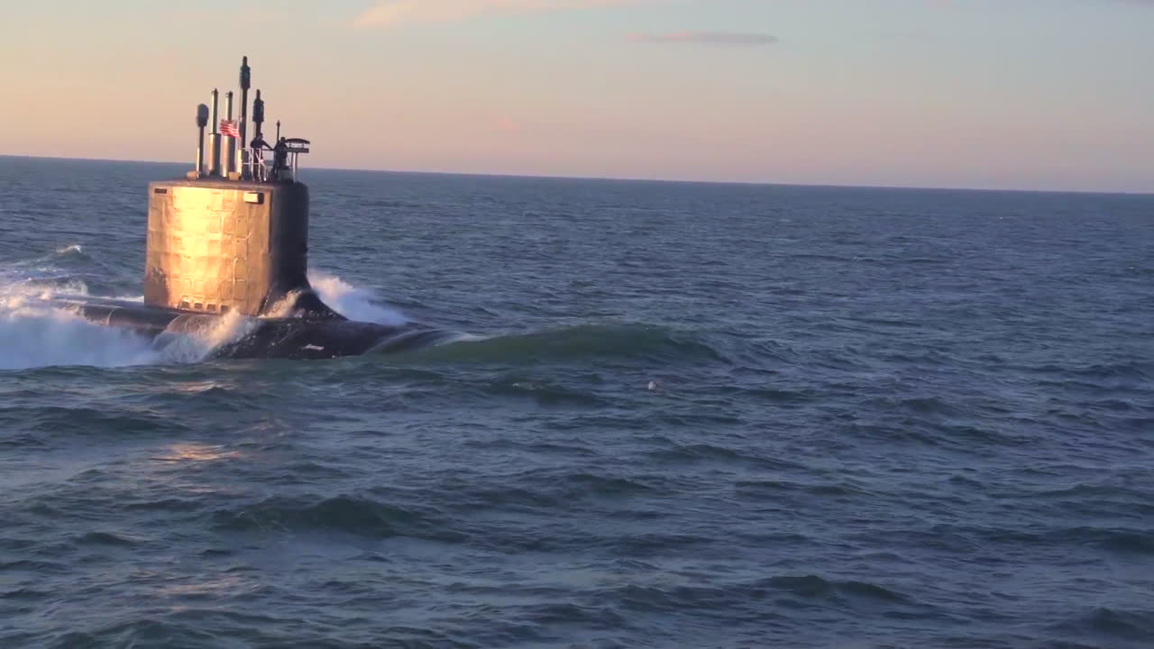antenas sobre un submarino en el mar con delfines saltando a través de la proa