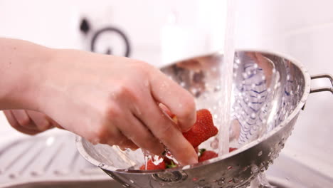 una mujer lavando fresas.