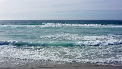 aerial shot towards horizon of waves rolling in on carmel-by-the-sea beach