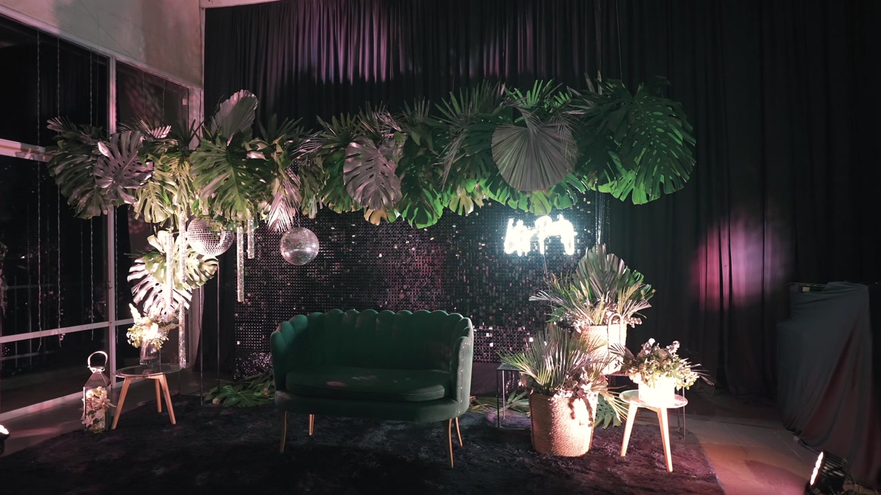 Panning shot of a luxury event decoration featuring tropical plants and elegant furniture