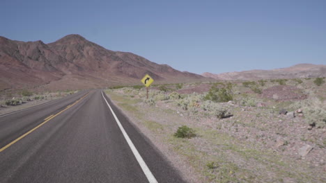 conducir más allá de una señal de tráfico en el desierto a cámara lenta