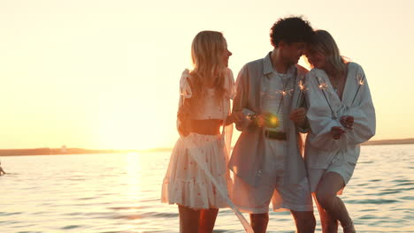 friends celebrating sunset at the beach with sparkler