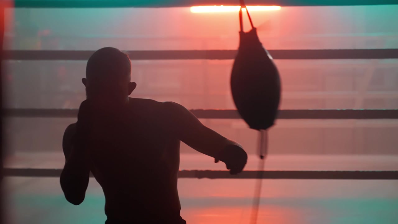 Silhouette di un pugile che si allena con un sacco veloce in un drammatico ring di pugilato.