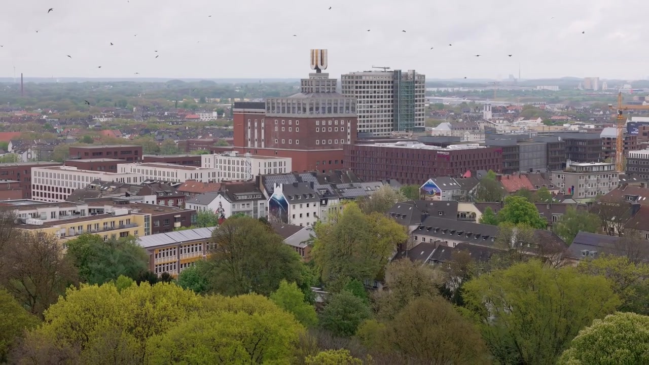 Luftaufnahme von Dortmund, Deutschland, mit dem ikonischen Dortmunder U Gebäude und fliegenden Vögeln.