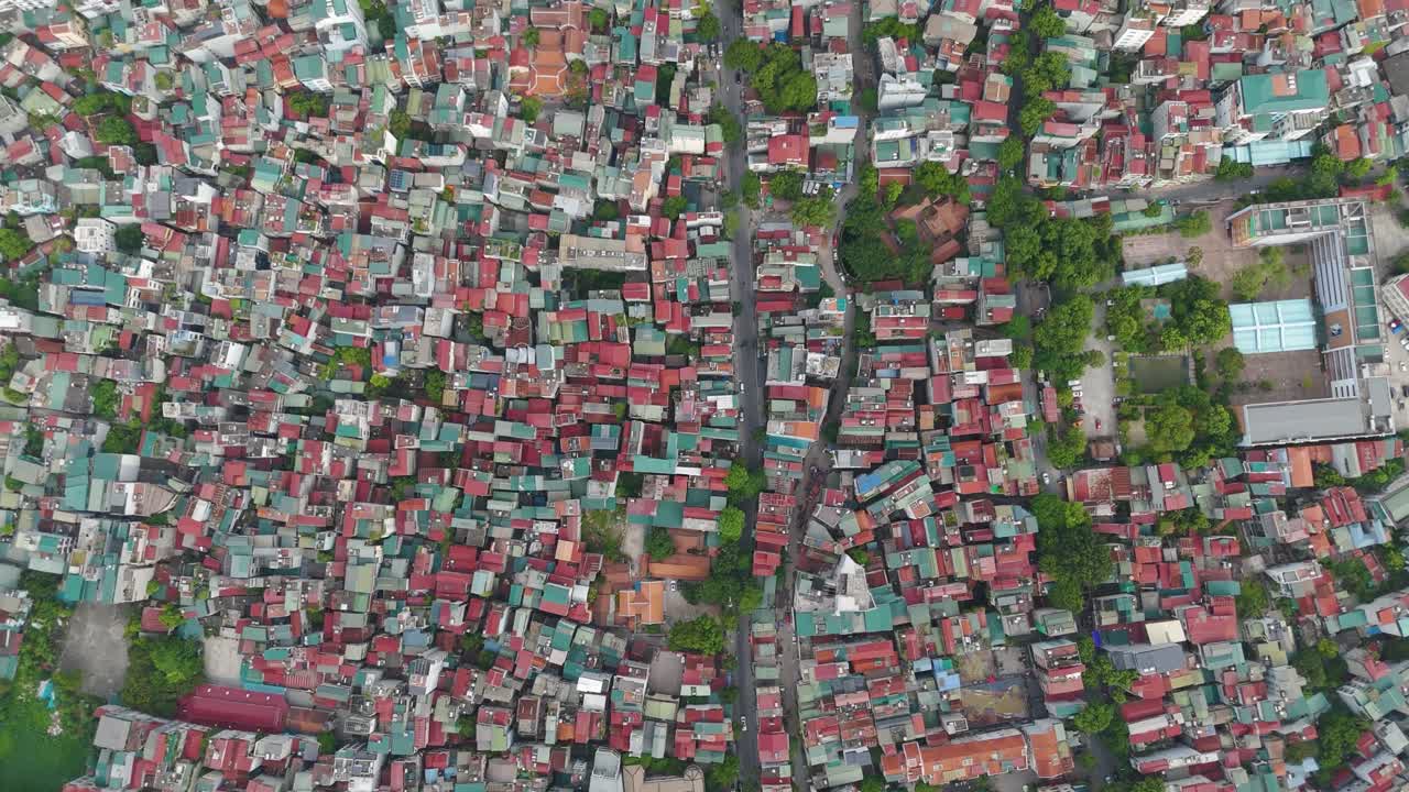 Top-down aerial drone view of Hanoi, Vietnam, showcasing a dense cityscape of colorful rooftops, narrow streets, and urban housing layout in vibrant detail
