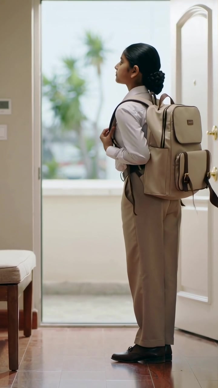 Vertical video: Preparing girl in uniform adjusting backpack at front door, leaving for school