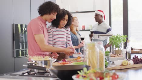 happy group of diverse friends cooking dinner in kitchen together