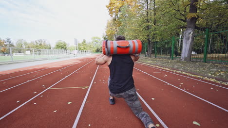 young man exercising outdoors. muscular built young athlete working out on stadium