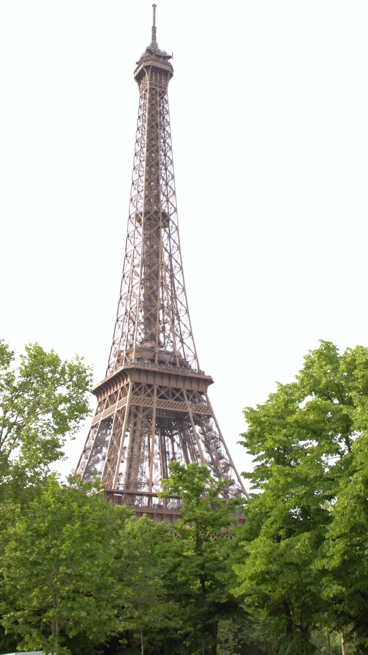 Una lenta panoramica della telecamera rivela la Torre Eiffel che si erge sopra lussureggianti alberi verdi del parco