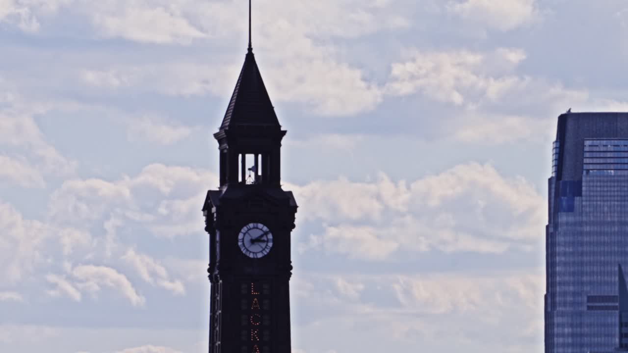 Detailed view of the historic Lackawanna clock tower against a cloudy sky, with a modern glass skyscraper partially visible