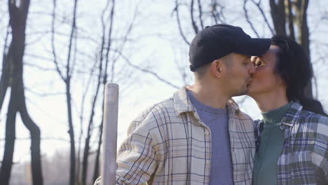 close-up view of a man is removing weeds in the countryside. the his partner approachs and kisses him