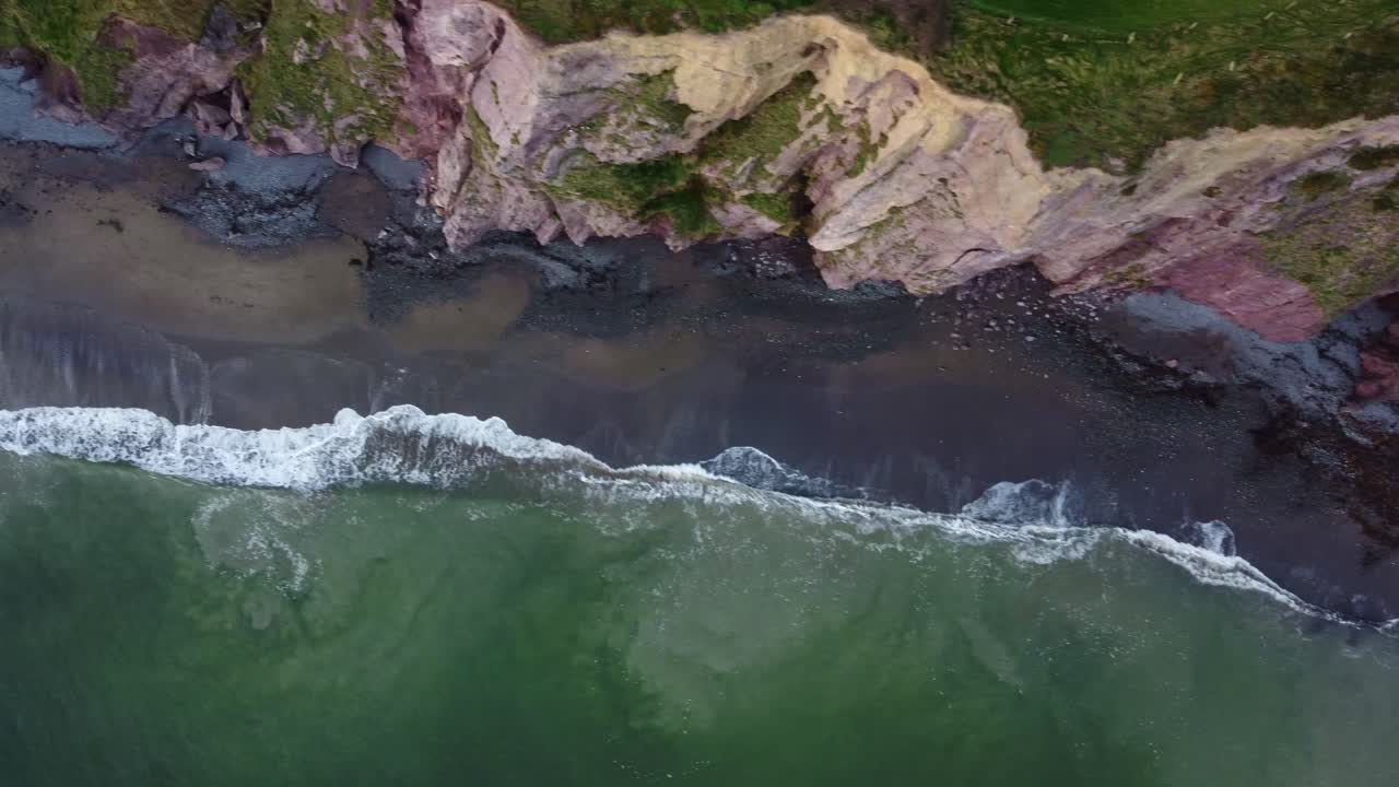 toma panorámica aérea de la playa y los acantilados de la costa de cobre en waterford, irlanda, en una tarde de invierno.