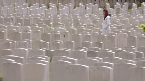 A-woman-in-a-white-coat-looks-at-headstones-of-the-Etaples-France-World-War-cemetery-military-graveyard-2