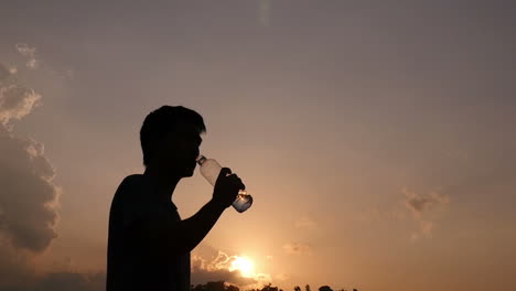 man drinking water at sunset