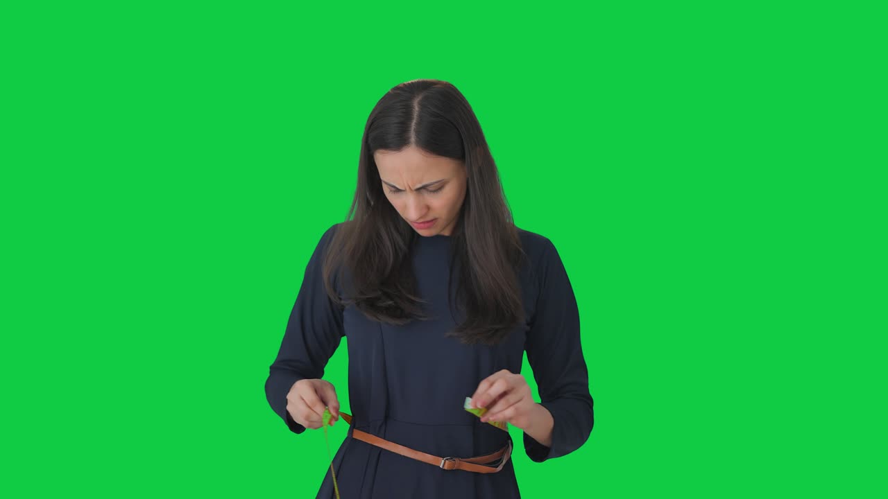 Sad Indian girl measuring her waist Green screen