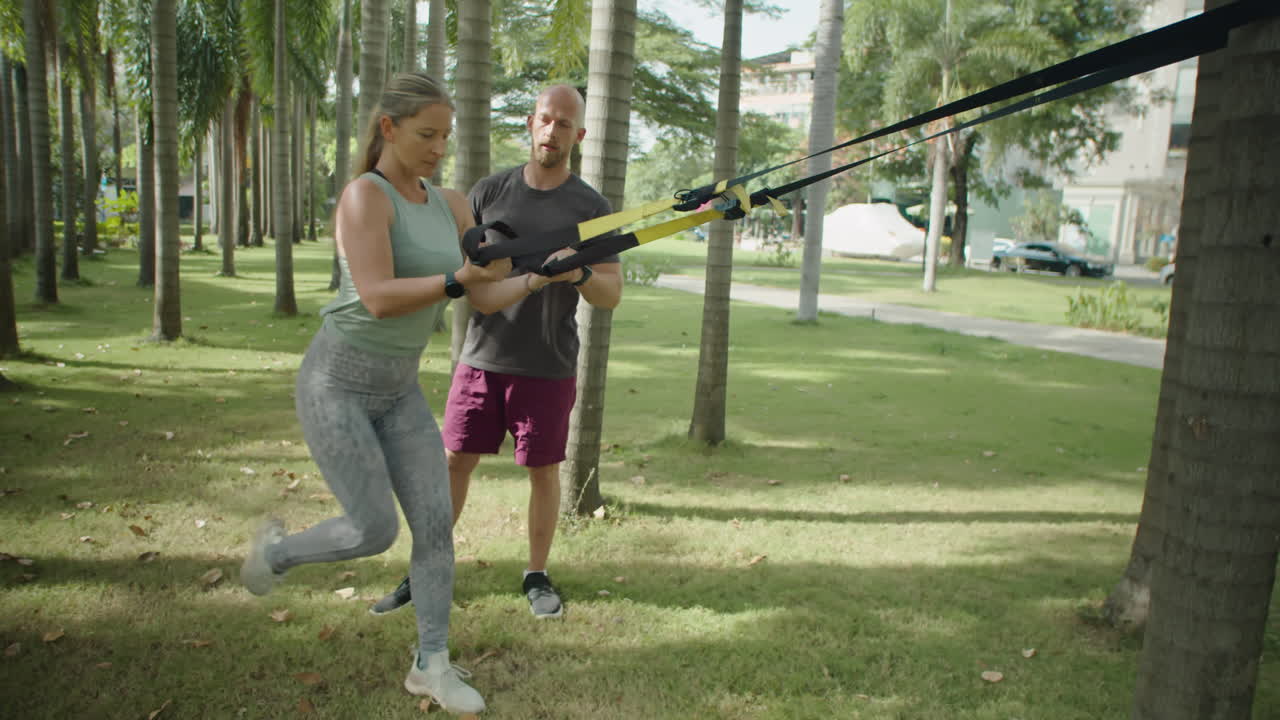 Woman Having Suspension Workout with Personal Trainer in Park