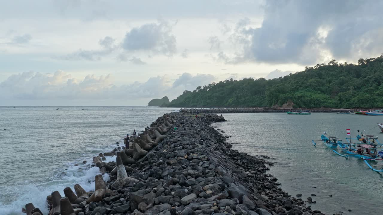 Spiaggia scenografica dell'Isola Rossa a Java, Indonesia, con frangiflutti e barche da pesca