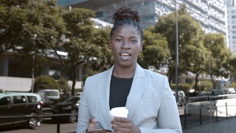 front view of a confident african-american businesswoman looking and speaking at the camera in the street