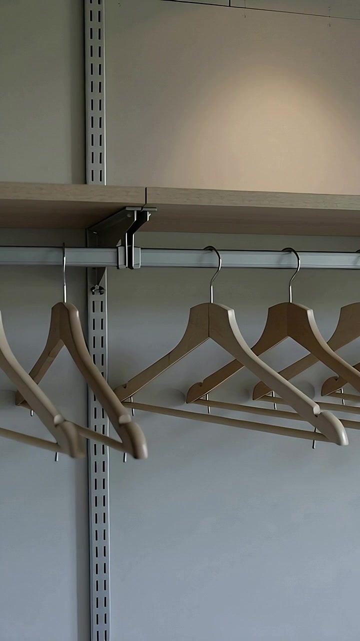 Vertical video: Panning camera showing wooden hangers on metal rail at retail shelf to record unit