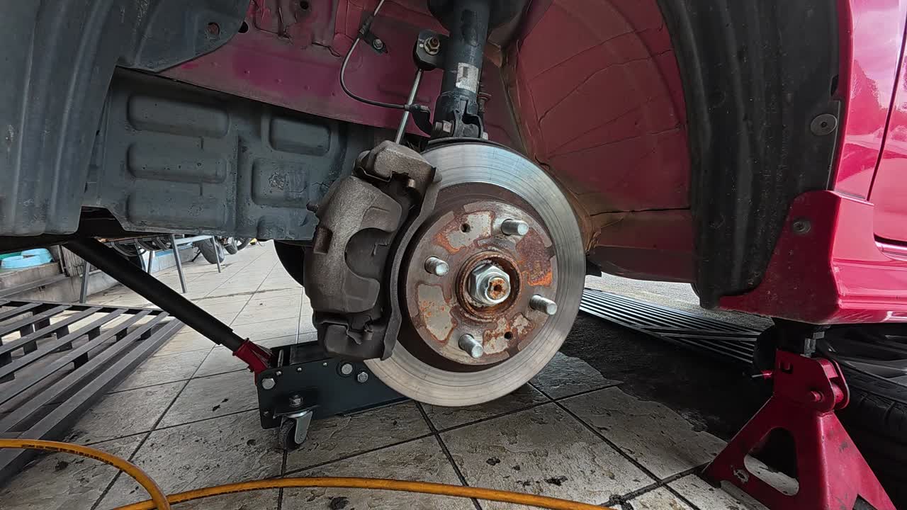 The car's exposed disk brake is ready for servicing at the workshop. The wheel has been removed for maintenance, ensuring optimal braking performance and safety.