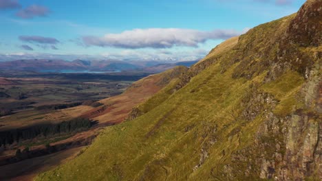 cinematic aerial footage of close fly along campsie fells cliffs revealing dumgoyne above glengoyne, stirlingshire