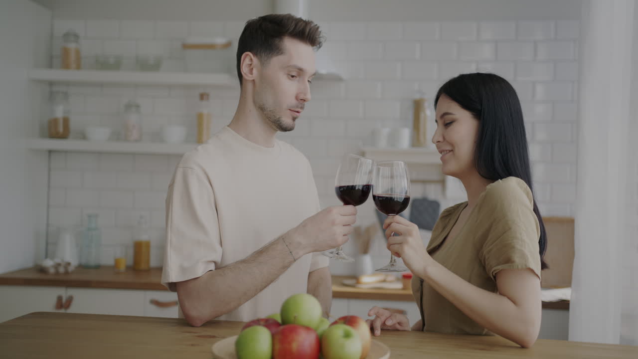 una pareja disfrutando del vino en la cocina.