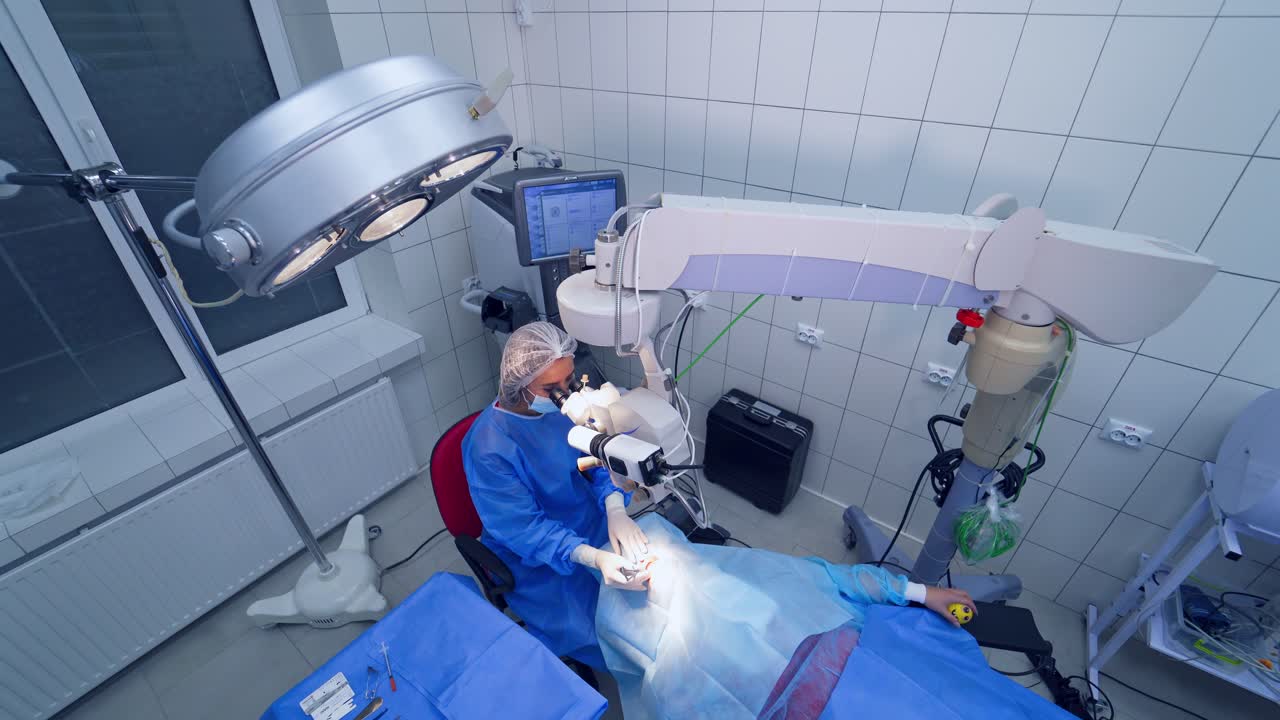 Making laser eye surgery. Surgeon looking into the microscope at the eye of patient at the operating room
