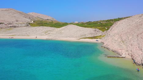 Aerial-of-beachgoers-at-a-quiet-sand-beach-at-Pag-Island,-Krk,-Croatia