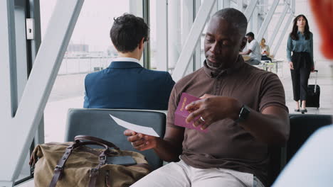 male passenger in airport departure lounge checking travel documents