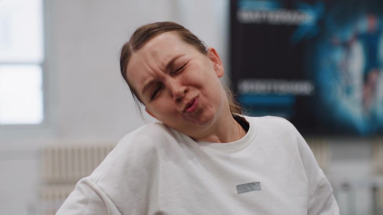 Donna ride dopo lo scambio. Sorriso luminoso durante la sessione di allenamento. Donna allegra si gode il gioco al chiuso. Giocatrice sorride luminosamente durante un'energica pratica di badminton in un ambiente interno.