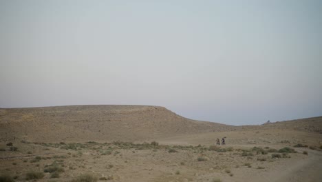 ciclistas de montaña en el ciclo de distancia junto a la colina del desierto