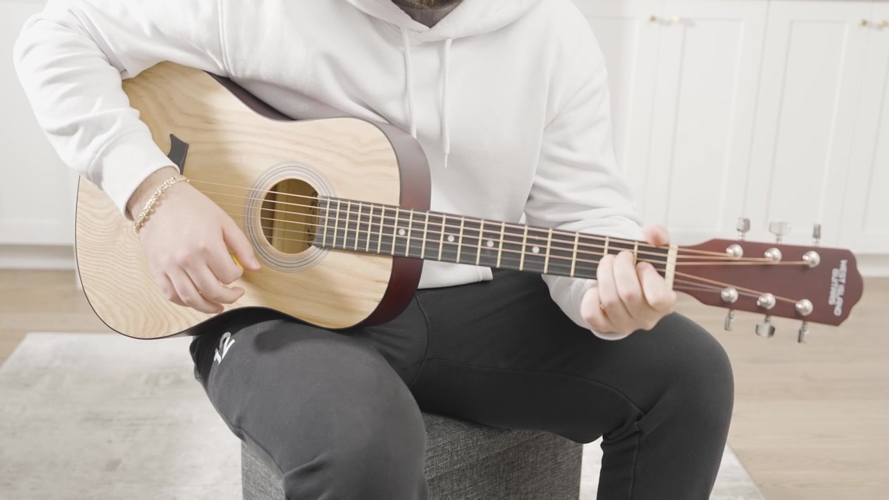 Ripresa statica al rallentatore di un giovane uomo che strimpella una chitarra acustica.