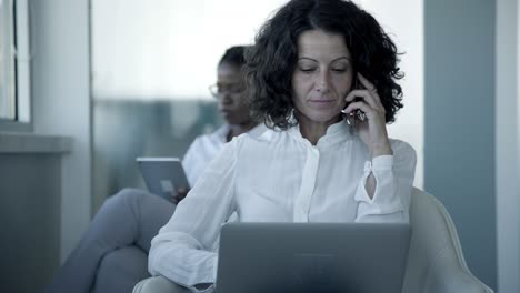 mujer de negocios seria con teléfono inteligente y computadora portátil