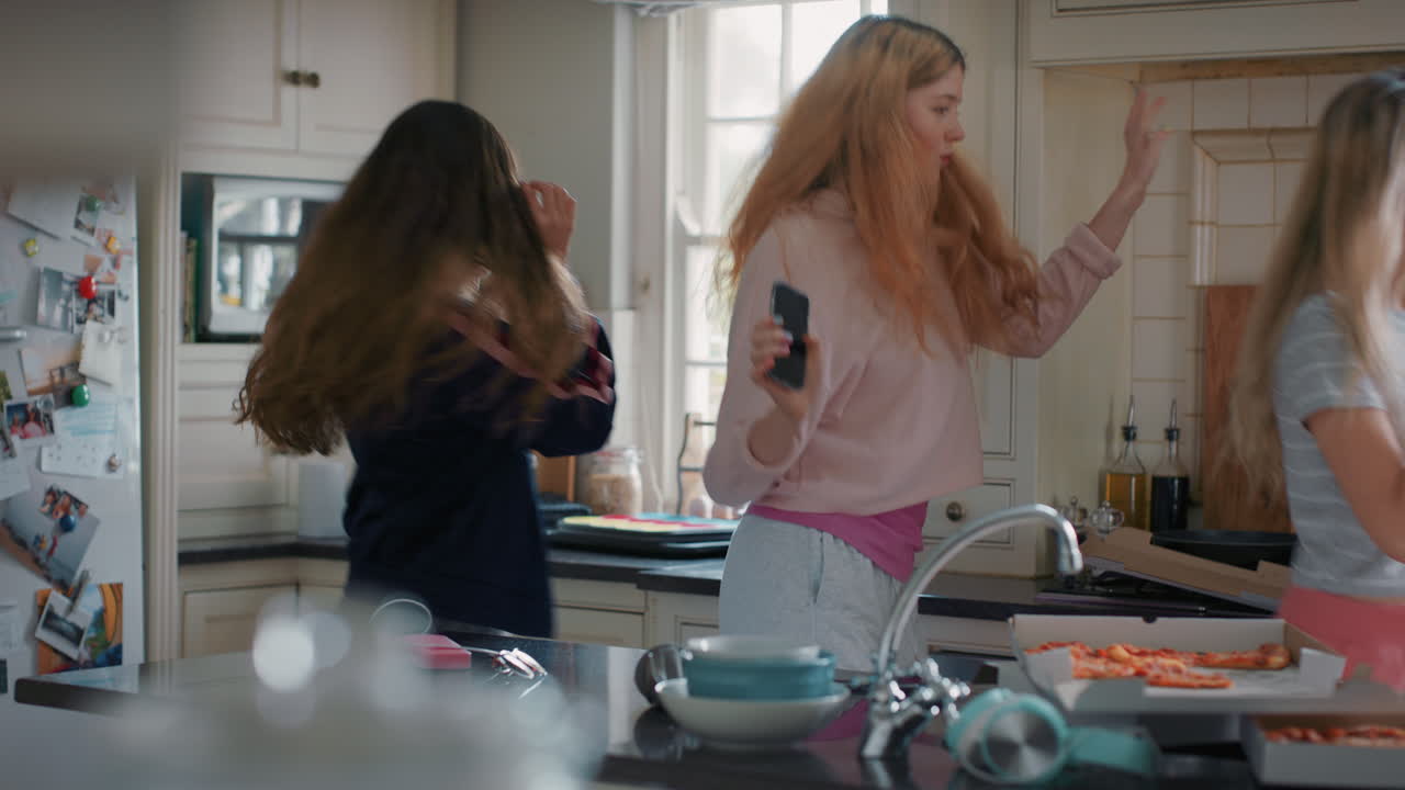 счастливые подростки танцуют на кухне, едят пиццу, веселятся, празднуют вместе, наслаждаются совместным времяпрепровождением в выходные.